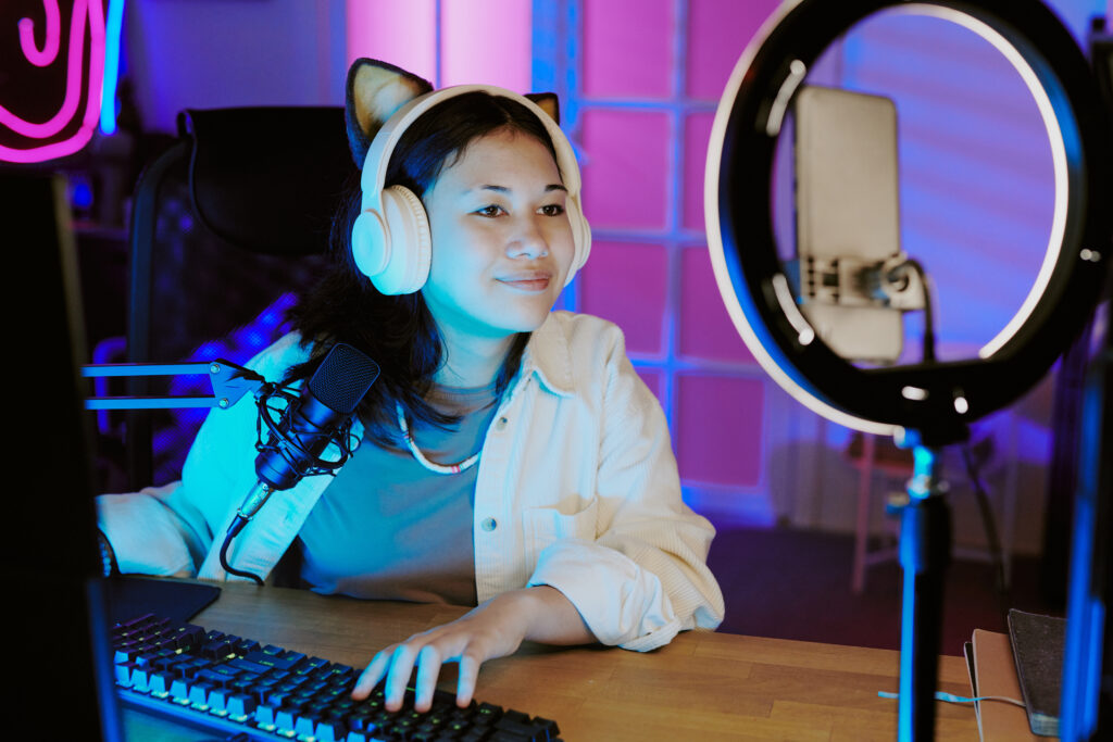 Teenage Girl Live Streaming Video Games With Headphones And Microphone